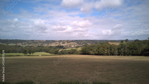 high drone footage of countryside fields with a view of the cloudy skies