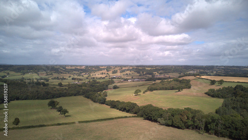 high drone footage of countryside fields with a view of the cloudy skies