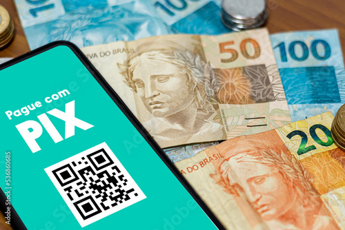 Pix on smartphone screen with multiple coins around. Pix is the new payment and transfer system of the Brazilian and Brazilian government. photo