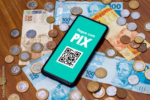 Pix on smartphone screen with multiple coins around. Pix is the new payment and transfer system of the Brazilian and Brazilian government.
