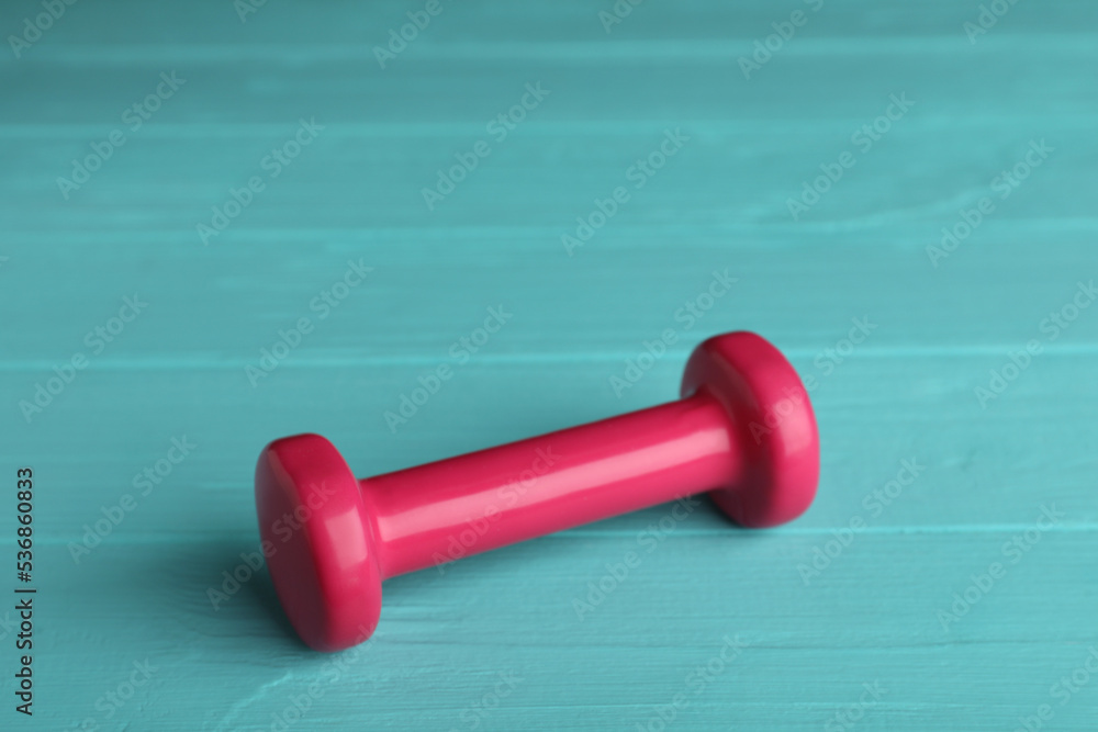 Pink vinyl dumbbell on turquoise wooden table Pink vinyl dumbbell on turquoise wooden table