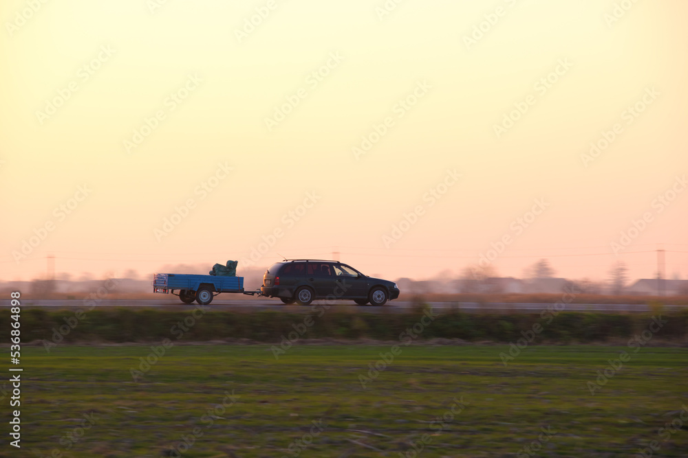 Fototapeta premium Tow truck vehicle with car carrier trailer driving on highway in evening