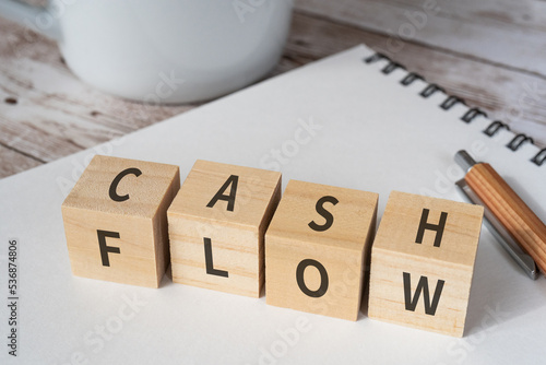 Photos CASH FLOWと書かれたブロック、コップ、ペン、ノート
