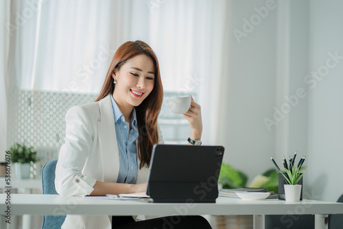 Successful attractive Asian businesswoman works from home with a tablet.