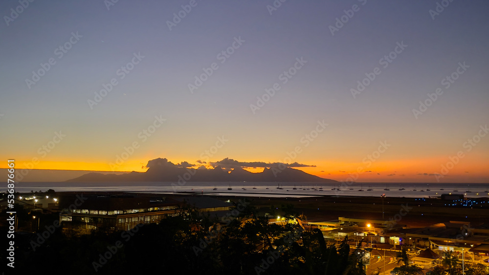 Sunset behind Moorea Island with Faa'a International Airport in the foreground at night
