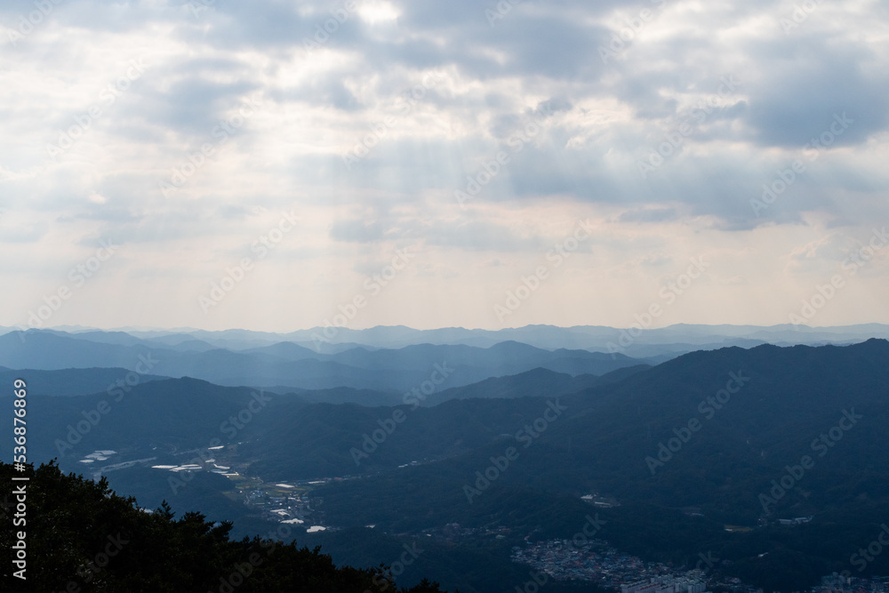 A ridge in the foreground under a majestic sky. A faint sunlight shining through the clouds. A ridge in the foreground under a majestic sky. A faint sunlight shining through the clouds.