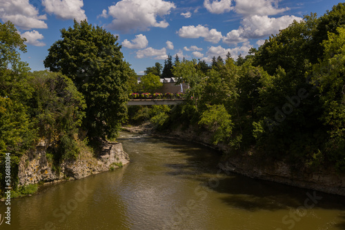 Nature landscape - bridge over the rapid Grand River  rocky banks  green trees  cloudy sky  day time. Fergus  Ontario  Canada