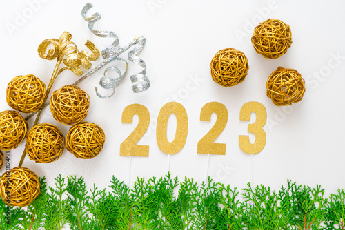 Flat lay of 2023 numbers in gold paper cutouts, christmas decoration and real green leaves. Happy new year and christmas concept