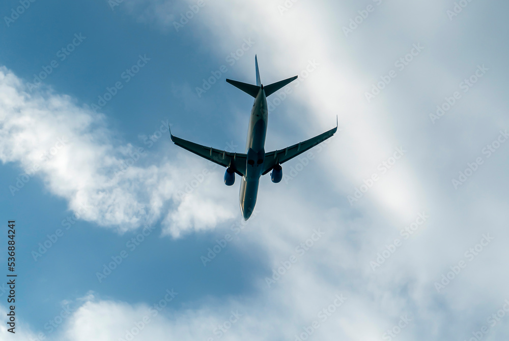 A white blue passenger plane with two engines against a cloudy sky. A white blue passenger plane with two engines against a cloudy sky.