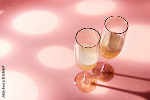 Glasses of champagne on pink background