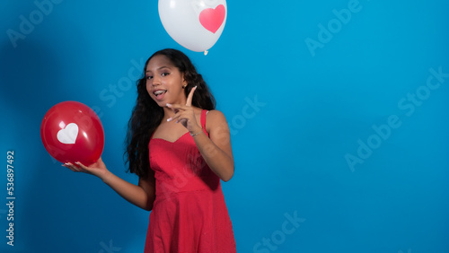 Niña en fondo azul, haciendo poses con globos, Vestido rojo, corazón. photo