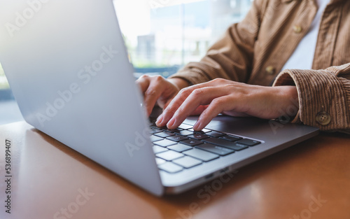 Closeup image of hands working and typing on laptop computer keyboard