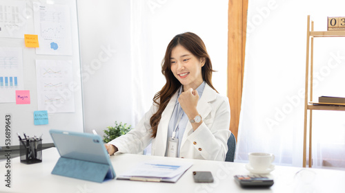 Joyful, Surprised or shocked Asian woman raised her arms all the way because she is very happy the boss gave her a big bonus making her very happy, Raise your hand, Smiling and screaming for success. photo