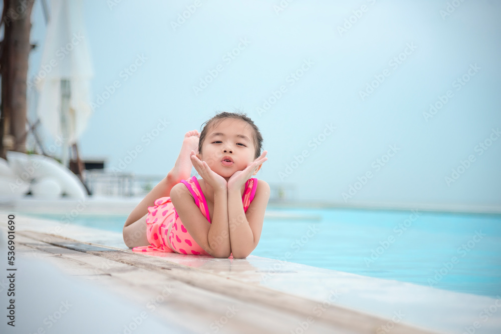 Toddler girl Kid swim playful in swimming pool summer time with pink swimwear in blue water at hotel swimming pool outdoor. Happy girl swim playful water splash with happiness on summer vacation Toddler girl Kid swim playful in swimming pool summer time with pink swimwear in blue water at hotel swimming pool outdoor. Happy girl swim playful water splash with happiness on summer vacation