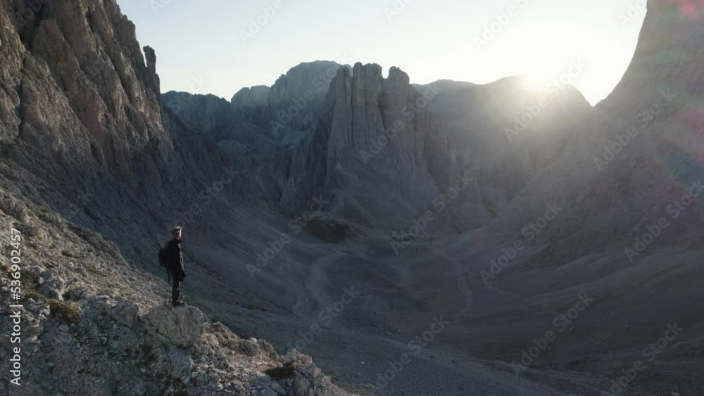 Fly over shot of a person in top of the mountain at sunrise in Torri Vajolet, Dolomites Fly over shot of a person in top of the mountain at sunrise in Torri Vajolet, Dolomites