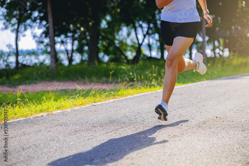 Crop image of silhouette of young woman running sprinting on road. Fit runner fitness runner during outdoor workout.