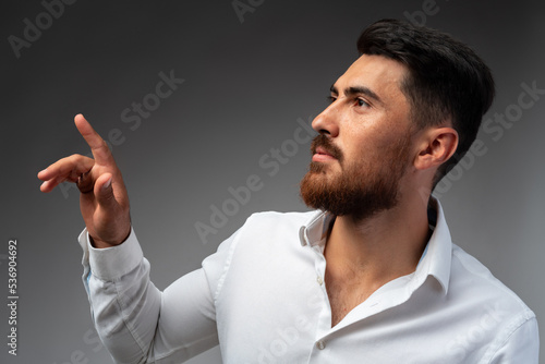 Young Arab businessman working with virtual screen over grey background. © fotofabrika