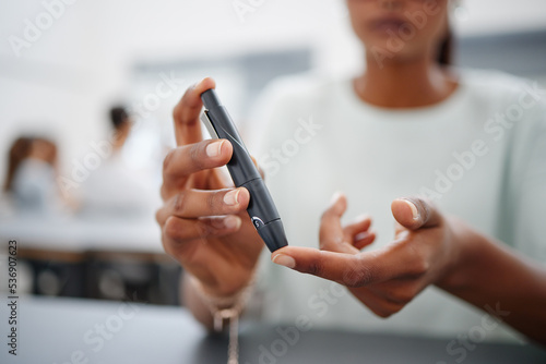 Diabetes  finger and black woman with blood sugar test on to check levels of student while sitting at desk. Healthcare  health and female prick to use glucose meter for insulin and wellness