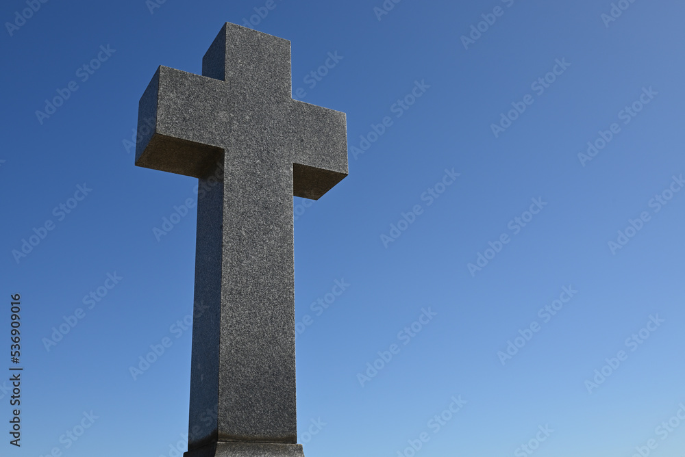 Chunky stone cross, or crucifix, with clear blue sky in the background