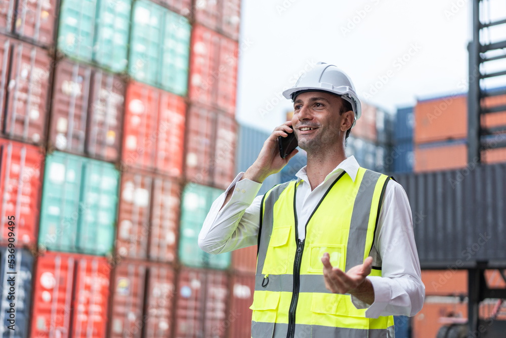 Handsome Caucasian businessman use phone to work in container terminal. Handsome Caucasian businessman use phone to work in container terminal.