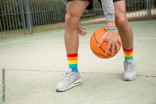 Man in sneakers and rainbow socks dribbling with a basketball ball