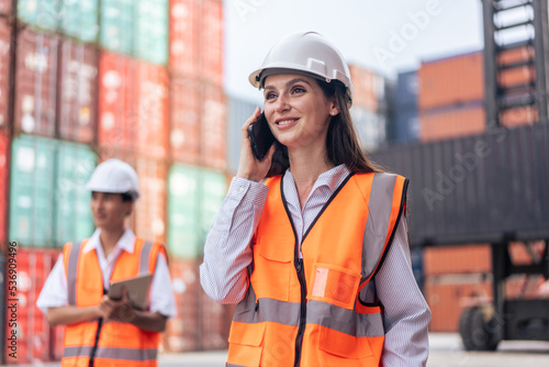 Caucasian businesswoman talk on phone while work in container terminal.