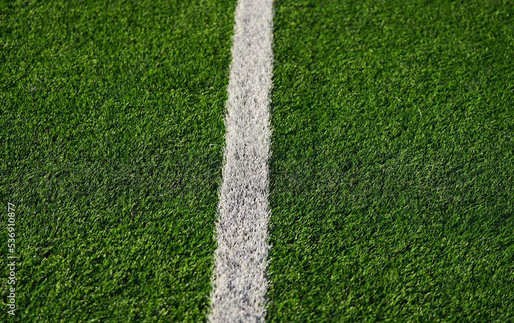 Fototapeta premium Close up detail field of the artificial grass from a brand new soccer field, view with the white marking line.
