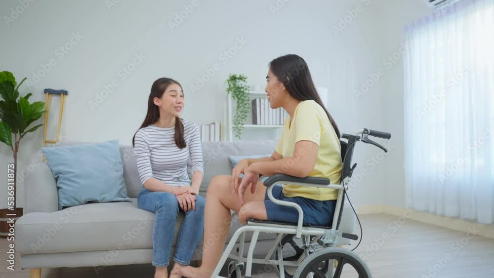 Asian young woman talking to female amputee friend sit on wheelchair. Asian young woman talking to female amputee friend sit on wheelchair.