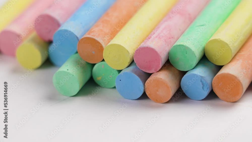 Multicolored pastel chalks stacked in a heap on a white paper background. Colourful collection. Rotation. Macro shot. Supplies for school and preschool creativity Multicolored pastel chalks stacked in a heap on a white paper background. Colourful collection. Rotation. Macro shot. Supplies for school and preschool creativity
