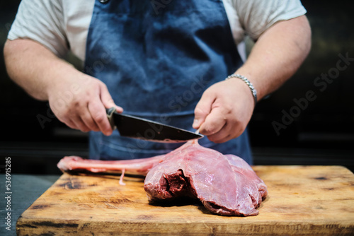 A butcher butchers a leg of lamb for grilling. Pitmaster prepares meat for smoking