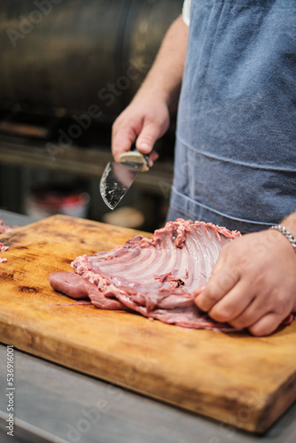 The butcher cleans the lamb ribs. Preparing meat for smoking or barbecue