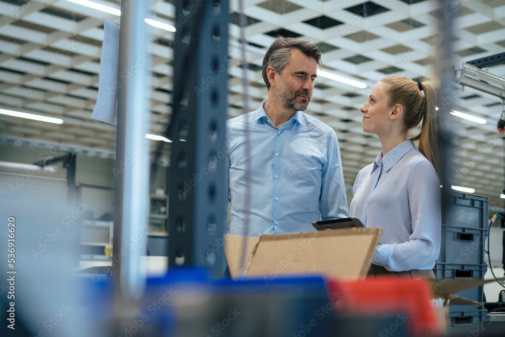 Smiling young manager looking at businessman in warehouse Smiling young manager looking at businessman in warehouse