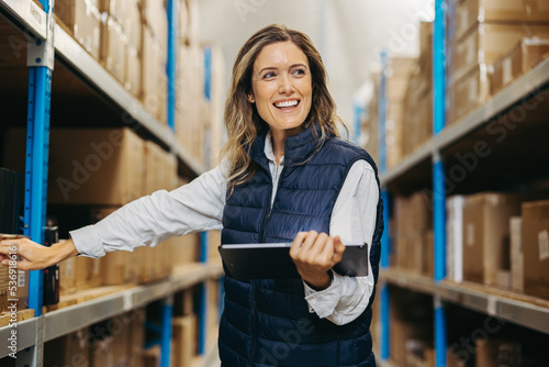 Cheerful warehouse manager doing inventory control with a digital tablet