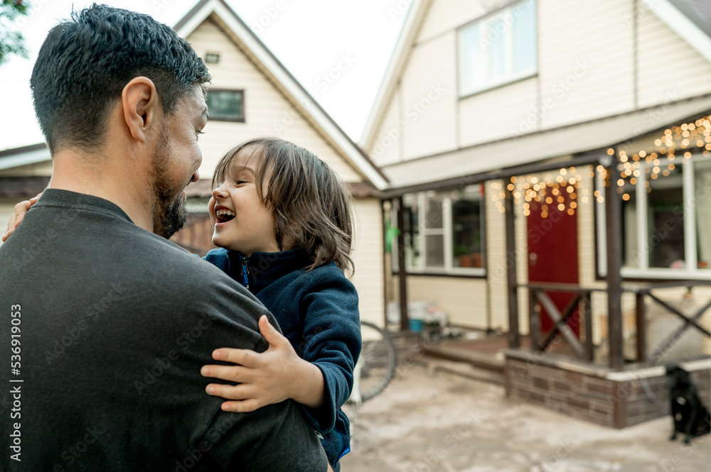 Happy father carrying son in front of house Happy father carrying son in front of house