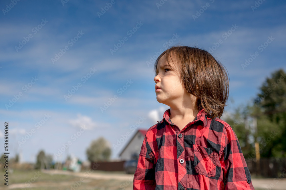 Thoughtful boy wearing plaid shirt on sunny day Thoughtful boy wearing plaid shirt on sunny day