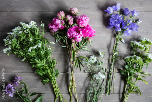 Bouquets of seasonal flowers lying on wooden surface photo