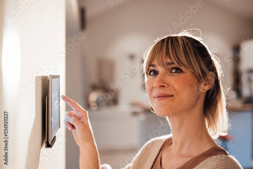 Smiling woman using smart home app on tablet at home photo