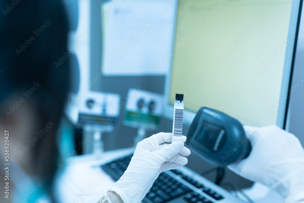 Woman scientist hand holding test tube barcode and scanner for automatic analysis machine in laboratory.Biologist working in modern laboratory with technological equipment. - obrazy, fototapety, plakaty 