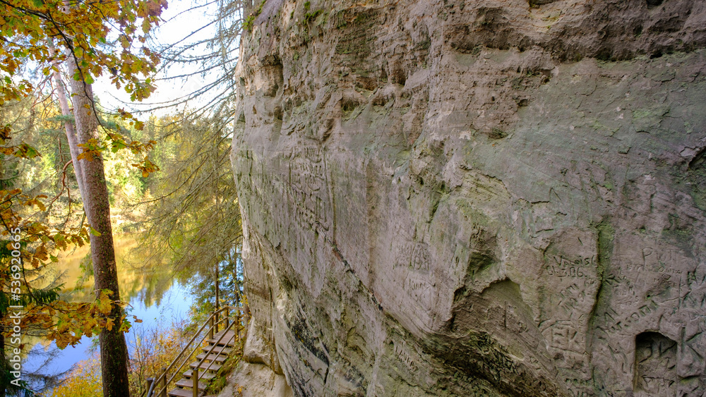 The large sandstone cliffs of Sietiniezis on the banks of the Gauja River in Latvia. tourist nature trail for hiking with wooden stairs. Gauja National Park in the vicinity of Valmiera, Autumn, The large sandstone cliffs of Sietiniezis on the banks of the Gauja River in Latvia. tourist nature trail for hiking with wooden stairs. Gauja National Park in the vicinity of Valmiera, Autumn,