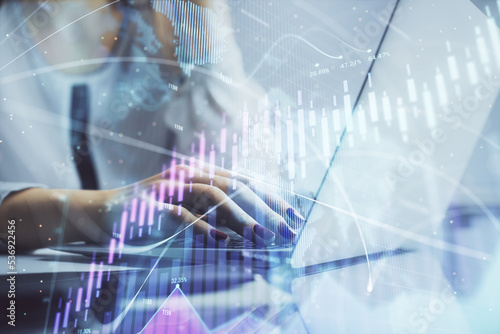 Double exposure of woman hands typing on computer and financial graph hologram drawing. Stock market analysis concept.