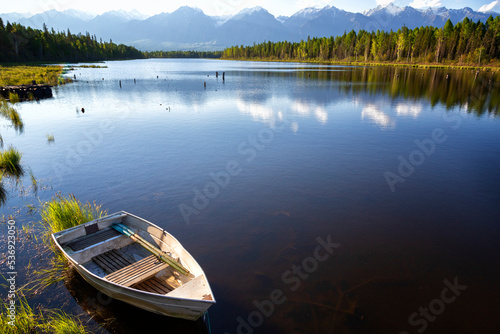 Landscape with mountains, lake and old wooden boat