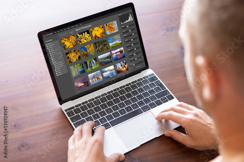 Man editing photo files on laptop computer