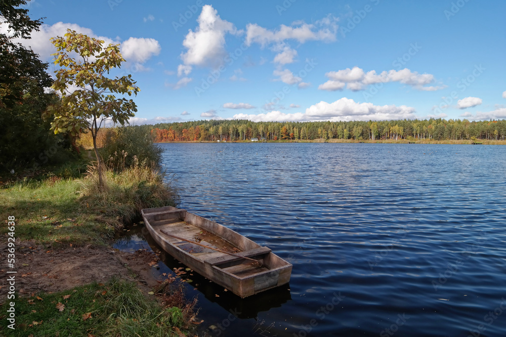 Widok na jezioro i łódkę w jesiennej odsłonie.
Widok na jezioro i łódkę w jesiennej odsłonie.