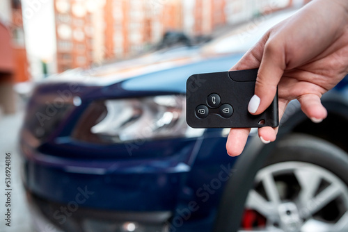 Man thumb presses button on remote control key removing alarm signal bright car alarm light