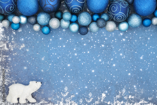 Christmas North Pole background concept with polar bear and blue sparkling tree baule decorations. Festive border composition for the Xmas holiday season on grunge. photo