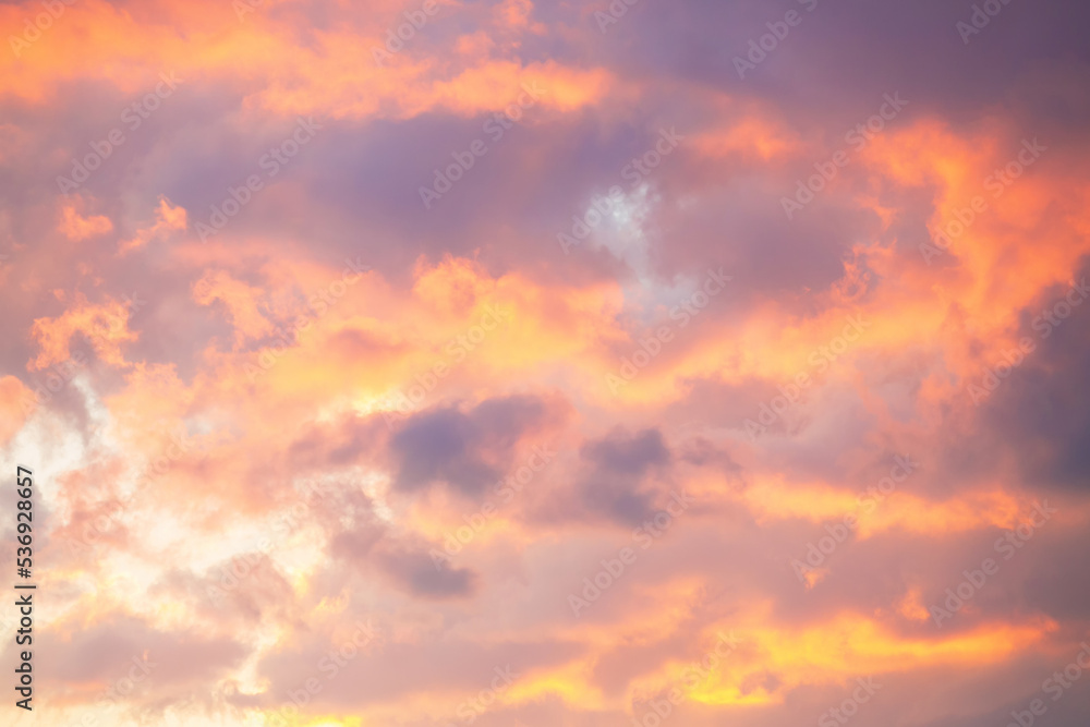 Romantic cumulus clouds on sunny day at sunset painted with sun, with some birds flying. Atmosphere multicolor background or wallpaper