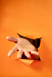 hand gesture on torn orange paper background