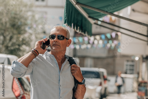 mature tourist man talking on mobile phone in the street