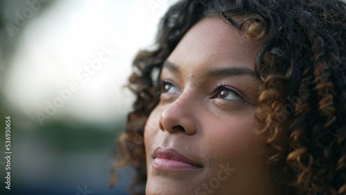 Pensive millennial African American young woman closeup face looking at sky. Thoughtful female person