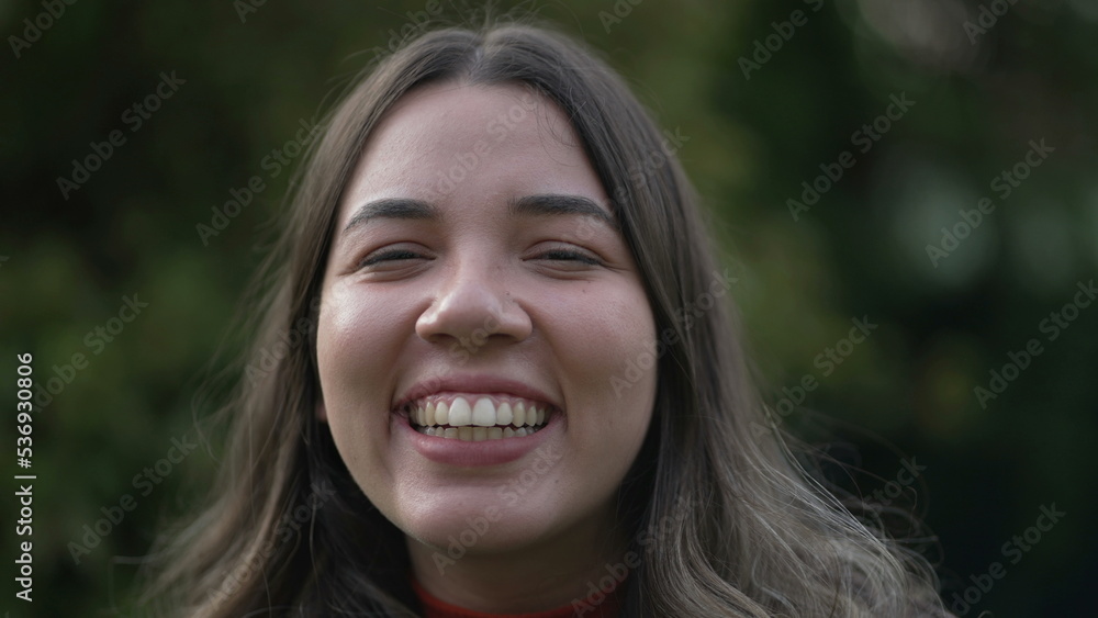 One happy casual Brazilian hispanic young woman laughing and smiling portrait face closeup standing outdoors